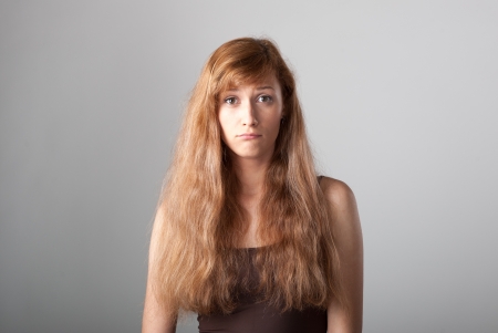 resentful casual caucasian girl with long brown hair on gray backgroundの写真素材