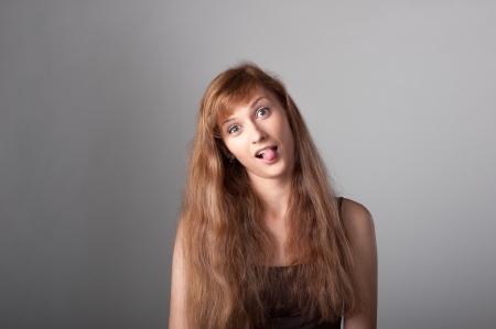 cheerful crazy casual caucasian girl with long brown hair on gray backgroundの写真素材