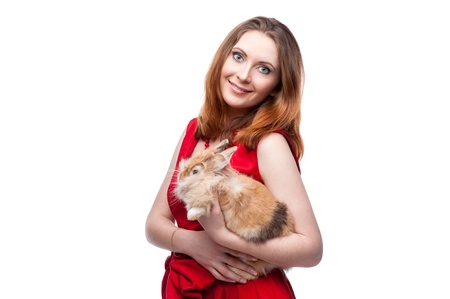 cheerful woman in red dress holding rabbit isolated on whiteの写真素材