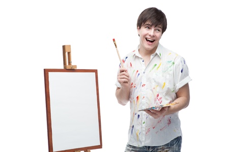 happy smiling painter standing near easel and holding palette and brushの写真素材