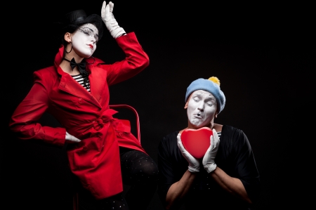 two funny mimes holding red heart isolated on black backgroundの写真素材