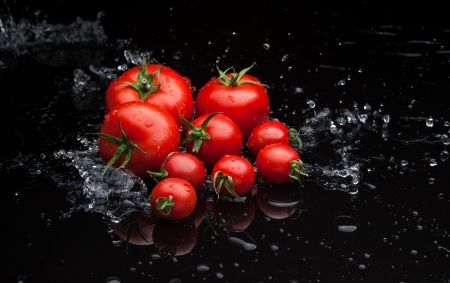 small group of fresh tomatoes lying over water splashesの写真素材
