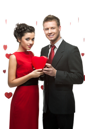 young smiling caucasian couple holding red heart isolated on white backgroundの写真素材