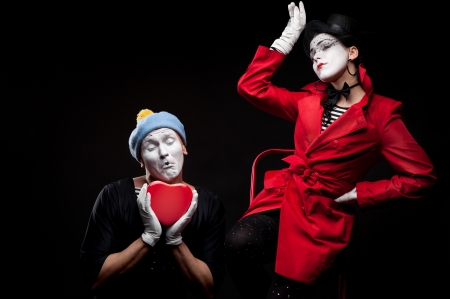 two funny mimes holding red heart isolated on black backgroundの写真素材