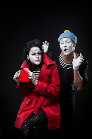 two funny mimes holding red heart isolated on black backgroundの写真素材