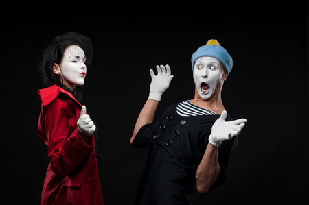 woman mime showing to male mime something to surprise himの写真素材
