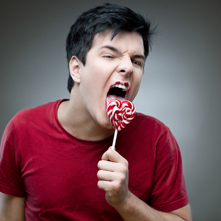casual caucasian crazy man holding lollipopの写真素材
