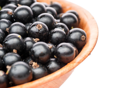 black currant berries lying in brown plate isolated on whiteの写真素材