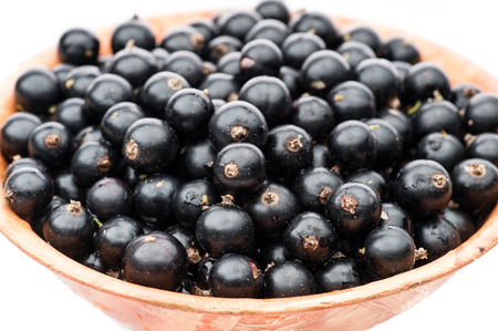 black currant berries in brown plate isolated on whiteの写真素材