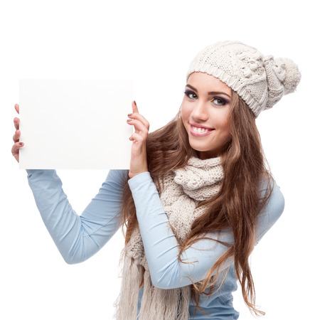 caucasian casual smiling young woman in winter clothing holding sign. isolated on whiteの写真素材