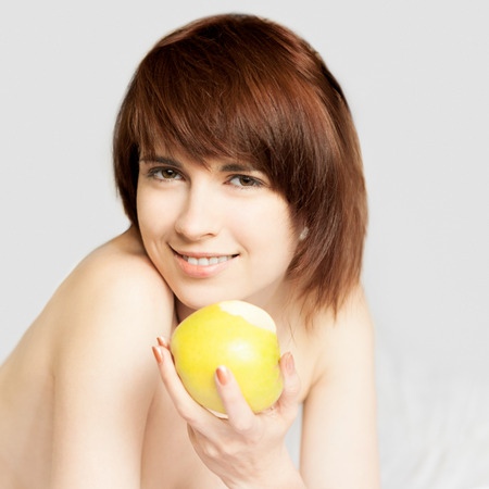 young red-haired caucasian girl lying with green apple and gently smiling while looking at cameraの写真素材