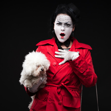 funny woman mime holding small fluffy dog and showing emotionsの写真素材
