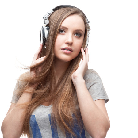 young casual caucasian girl with headphones listening to music isolated on whiteの写真素材