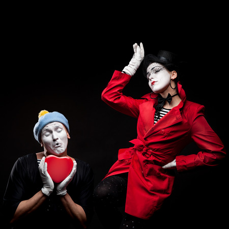 two funny mimes holding red heart isolated on black backgroundの写真素材