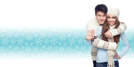 happy smiling young couple standing over winter snowflakes backgroundの写真素材
