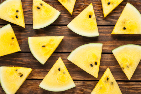 yellow ripe watermelon slices on dark old wooden background top viewの写真素材