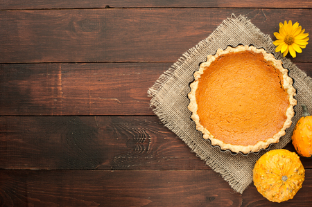 pumpkin homemade pie on wooden background arranged with food ingredients top viewの写真素材