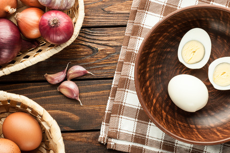 chicken eggs in basket decorated with food ingredients on an old wooden tableの写真素材