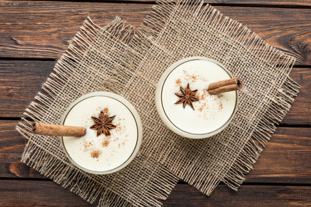 eggnog cocktail in glasses arranged with christmas decoration on wooden table top viewの写真素材