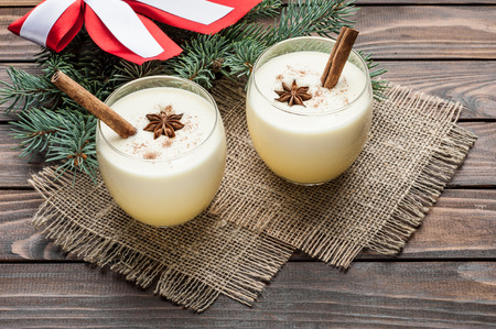 eggnog cocktail in glasses arranged with christmas decoration on wooden table top viewの写真素材