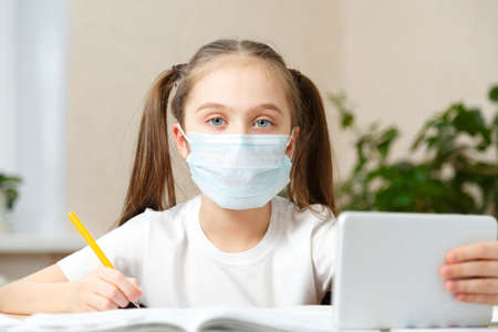 Schoolgirl studying homework during her online lesson at home, online education and online school concept, home schooler. Distance or remote learningの写真素材