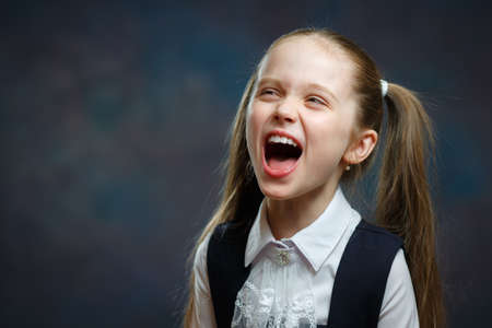 Joyful Elementary Schoolgirl Emotional Portrait. Pretty Caucasian Girl Laugh Front Close-up Photo. Cute Carefree Child Wear Typical Black and White Uniform School System Concept Shotの写真素材