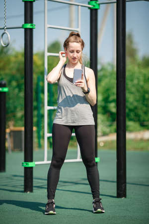 Young Woman Uses Smartphone at the Athletic Field.