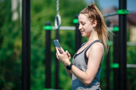 Sports and fitness outside the gym. Young fit woman with perfect body in sportswear with smartphone...