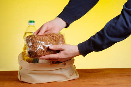 The hands of the volunteer put the basic necessities in a bag for donations to the elderly....