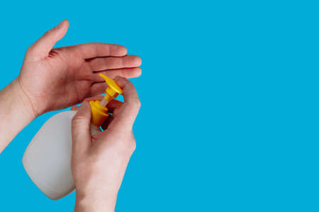 Container with liquid soap and hands on a blue background. Disinfection during the epidemic COVID -...