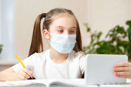 Schoolgirl studying homework during her online lesson at home, online education and online school concept, home schooler. Distance or remote learningの写真素材
