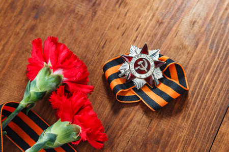 Order of the patriotic war 1st class and two red carnations. Still life dedicated to Victory Day. 9 May.の写真素材