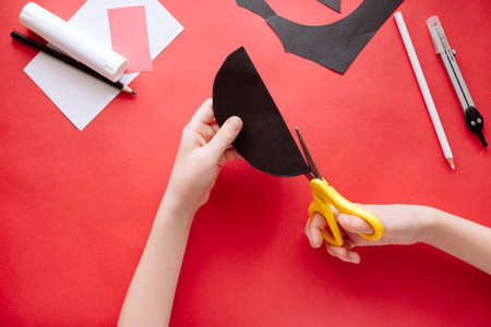 How to make bat out of paper at home. Hands making craft out of paper. Step by step photo instruction. Step 3. Cut the circles into two parts. Children DIY art project.の写真素材