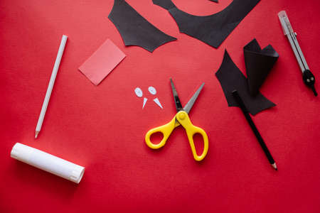 How to make bat out of paper at home. Hands making craft out of paper. Step by step photo instruction. Step 9. Eyes and fangs ready. Children DIY art project.の写真素材