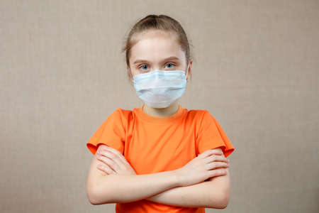 Portrait of a Little girl in a medical mask. Kid patient stands against the wall background, copy space for text.の写真素材