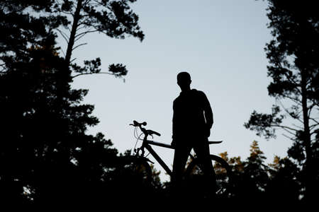 A guy with a bicycle on a sky background. Silhouette.の写真素材