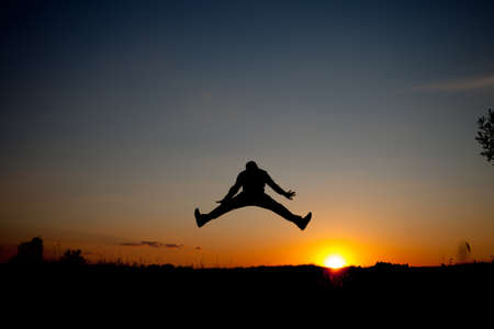 The silhouette of the man jumping with sunset background, concept of happiness, joy, joyful life