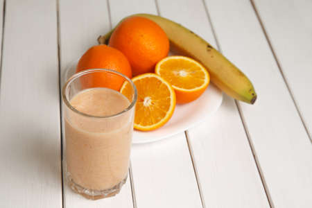 Orange smoothie in glass on wooden tableの写真素材
