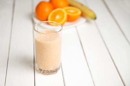 Orange smoothie in glass on wooden tableの写真素材