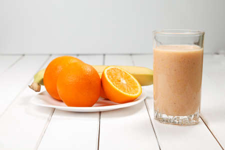 Orange smoothie in glass on wooden tableの写真素材