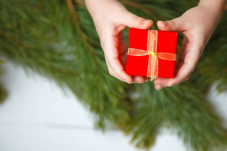 holidays, present, childhood and happiness concept - close up of child hands with gift box over christmas tree background. top viewの写真素材