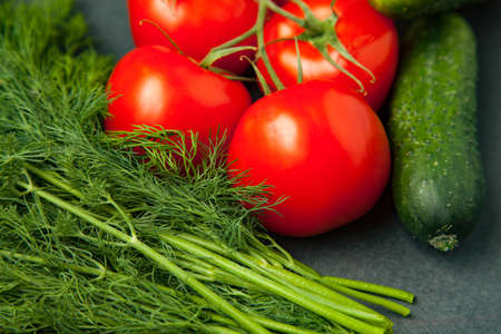 Background of blank black color with fresh healthy vegetables - cucumber, dill and tomatoes. close upの写真素材