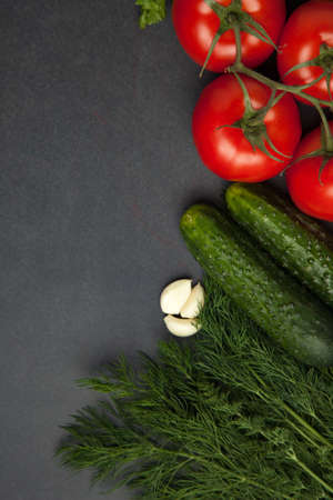 Background of blank black color with fresh healthy vegetables, green onion,, cucumber, tomatoes. Empty space for text. Top view.の写真素材