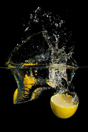 Fresh lemon drop in the water on black backgroundの写真素材