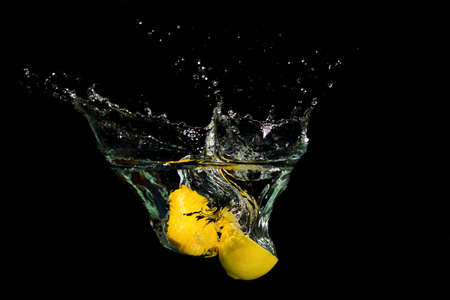 Fresh lemon drop in the water on black backgroundの写真素材