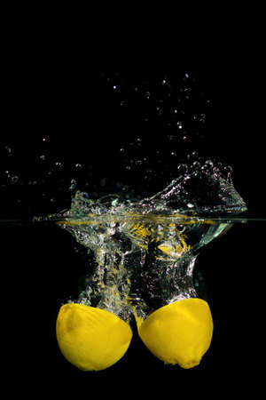 Fresh lemon drop in the water on black backgroundの写真素材