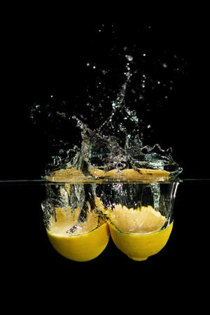 Fresh lemon drop in the water on black backgroundの写真素材