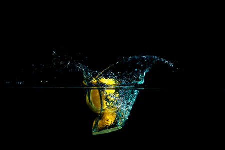 Fresh lemon drop in the water on black backgroundの写真素材