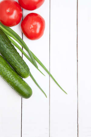set fresh vegetables on white wooden background. omato, cucumber and green onion. top viewの写真素材