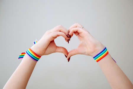 Womens making hand heart with gay pride rainbow colors sport wristbands.